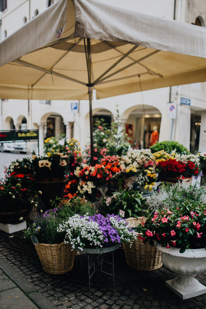 A street corner stand with various multi-coloured bouquets of flowers under a patio umbrella